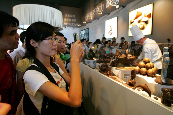 A visitor takes photos on delicate chocolate at Belgium-EU Pavilion of the Expo Park in Shanghai, Aug 21, 2010. Visitors could learn how to make chocolate at the Belgium-EU Pavilion. Some chocolate displayed in the pavilion is made into figures of Shanghai&apos;s landmark buildings and Expo mascot. [Xinhua]