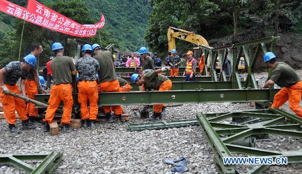 Workers make efforts to set up a bridge to replace the destroyed one across the Dongyuegu River in mudslide-hit Gongshan, southwest China's Yunnan Province, Aug. 22, 2010.