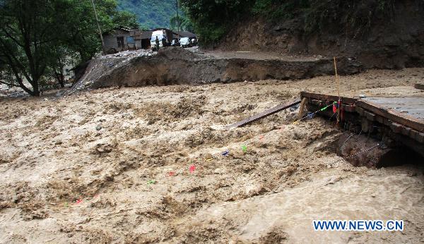 Torrential water of Dongyuegu River rushes across a damaged road in mudslide-hit Gongshan, southwest China's Yunnan Province, Aug. 22, 2010.