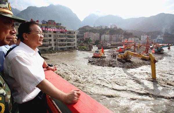 Chinese Premier Wen Jiabao stands on the Chengjiang Bridge to inspect floodwater of the barrier lake as machines dredge the channel of the Bailongjiang River in landslide-hit Zhouqu County, Gannan Tibetan Autonomous Prefecture in northwest China's Gansu Province, Aug. 22, 2010.