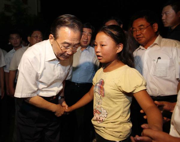 Chinese Premier Wen Jiabao (L, front) talks with a girl as he visits a middle school serving as a relocation center in landslide-hit Zhouqu County, Gannan Tibetan Autonomous Prefecture in northwest China's Gansu Province, Aug. 21, 2010. Wen made an inspection tour in Zhouqu on Aug. 21-22.