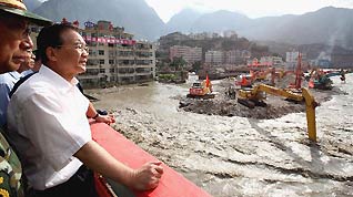 Chinese Premier Wen Jiabao stands on the Chengjiang Bridge to inspect floodwater of the barrier lake as machines dredge the channel of the Bailongjiang River in landslide-hit Zhouqu County, Gannan Tibetan Autonomous Prefecture in northwest China's Gansu Province, Aug. 22, 2010.