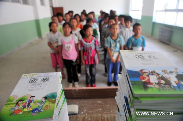 Primary school students line up to get their new textbooks in the landslide-hit Zhouqu County, northwest China's Gansu Province, Aug. 24, 2010. 