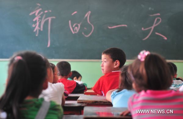 Lei Zhengguo (C, in red), together with his classmates, waits to get their new textbooks in the landslide-hit Zhouqu County, northwest China's Gansu Province, Aug. 24, 2010. 