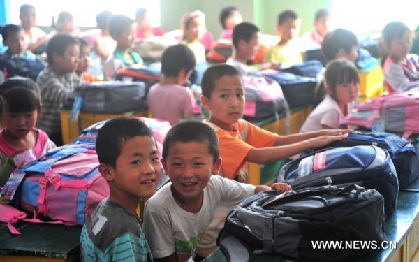 Primary school students sit in their classroom after get their new schoolbags in the landslide-hit Zhouqu County, northwest China's Gansu Province, Aug. 24, 2010. 