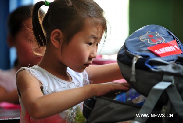 Zhang Qingqing looks into her new school bag in the landslide-hit Zhouqu County, northwest China's Gansu Province, Aug. 24, 2010. 