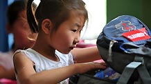Zhang Qingqing looks into her new school bag in the landslide-hit Zhouqu County, northwest China's Gansu Province, Aug. 24, 2010.