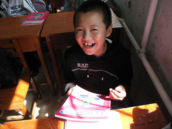 A student smiles as he receives new text books in the classroom, Aug 23, 2010.