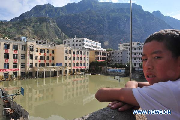 A boy looks at a flooded campus after a significant water decline in Zhouqu County, northwest China's Gansu Province, Aug. 24, 2010. After days of dredge work in the Bailong River, Zhouqu witnessed a significant decline of the water level, flood on some of the street began to subside.
