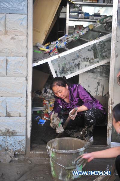 A woman cleans up the mud outside a store after a significant water decline in Zhouqu County, northwest China's Gansu Province, Aug. 24, 2010. 