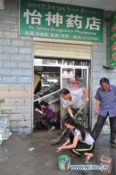 People clean up the mud outside a store after a significant water decline in Zhouqu County, northwest China's Gansu Province, Aug. 24, 2010.