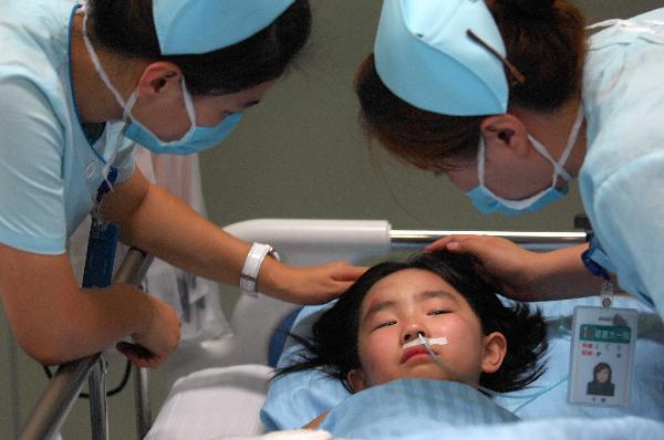 Nurses comfort a girl at the First Affliated Hospital of Harbin Medical University in Harbin, capital of northeast China's Heilongjiang Province, Aug. 25, 2010. 