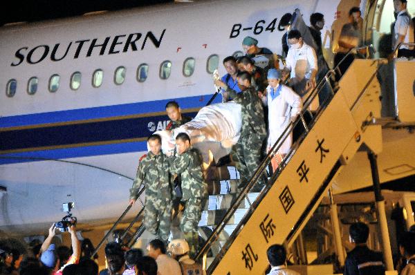 Rescuers carry a injured passenger off the plane at the Harbin Taiping International Airport in Harbin, capital of northeast China's Heilongjiang Province, Aug. 25, 2010. 