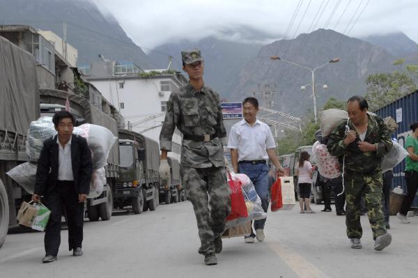 A soldier helps landslide victims move into a newly established shelter site in Zhouqu County, northwest China's Gansu Province, Aug. 25, 2010.