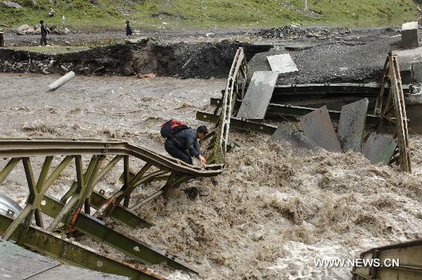 A man tries to get across a river through a damaged bridge in Nagqu County, southwest China's Tibet Autonomous Region, Aug. 29, 2010. 