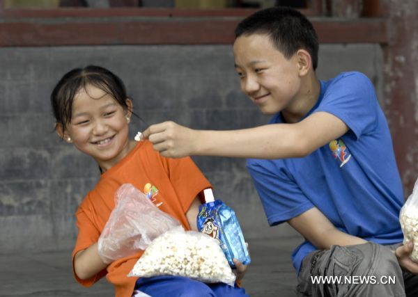 Shang Haiwang (R) and his younger sister Shang Haijiao share popcorn in the Summer Palace in Beijing, capital of China, Aug. 30, 2010. 