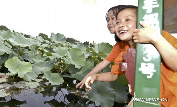 Gao Wenyan(R) and Shang Haijiao view the scenery of lotus flowers in the Summer Palace in Beijing, capital of China, Aug. 30, 2010.