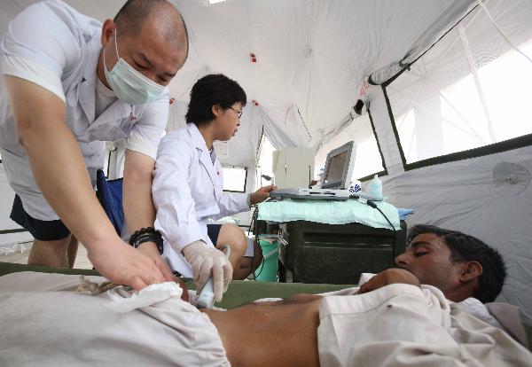Chinese medical workers check the condition of a Pakistani flood victim at a mobile hospital set up by a Chinese rescue and relief team in Thatta, one of the worst-hit regions in Pakistan, on Aug. 31, 2010. The Chinese team has received 1,451 patients up to Monday night. 