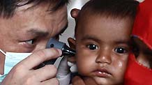 A Chinese doctor checks the ear of a Pakistani child at a mobile hospital set up by a Chinese rescue and relief team in Thatta, one of the worst-hit regions in Pakistan, on Aug. 31, 2010.