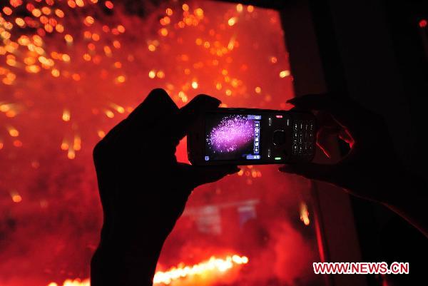 A citizen takes photos of fireworks which is set off to celebrate the 30th anniversary of the establishing of Shenzhen Special Economic Zone in Shenzhen, south China&apos;s Guangdong Province, Sept. 6, 2010.