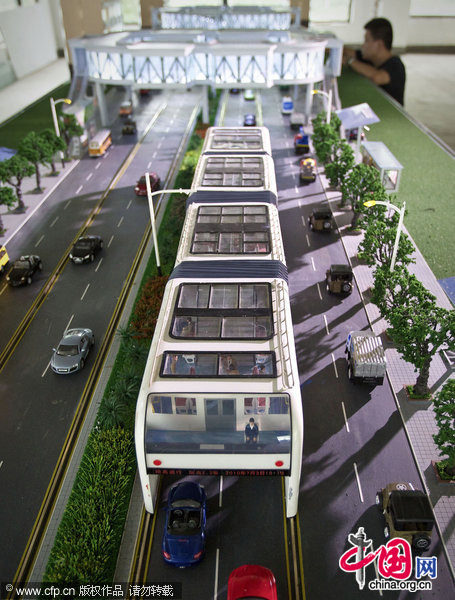 A visitor looks at a scale model of 'straddle bus'. The 'straddle bus', invented by Shenzhen Huashi Future Parking Equipment Co. Ltd., on display at an office showroom in Beijing, Friday, Sept. 3, 2010. 
