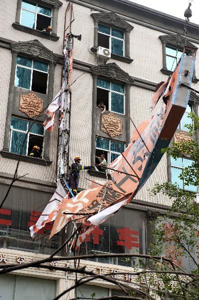 Firefighters pull down an advertisement board damaged by the typhoon Meranti in downtown Shishi, southeast China's Fujian Province, Sept. 10, 2010.