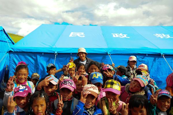 Gelhaigyu Gyaco of Tibetan ethnic group poses for a group photo with students in front of a tent classroom in Zhamang of Batang Village, Yushu Tibetan Autonomous Prefecture, northwest China's Qinghai Province, on Aug. 25, 2010.