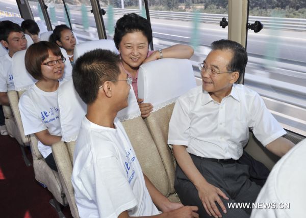 Chinese Premier Wen Jiabao (R, front) talks with a student from Beijing Normal University on the way to a middle school in Xinglong County, north China's Hebei Province on Sept. 10, 2010. 