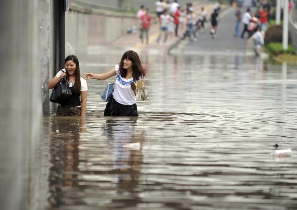 Two girls wade through the waterlogged Jiangnan Street in Hangzhou, capital of east China's Zhejiang Province, Sept. 11, 2010. 