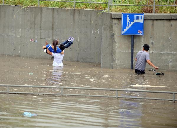 People wade through the waterlogged Jiangnan Street in Hangzhou, capital of east China's Zhejiang Province, Sept. 11, 2010.