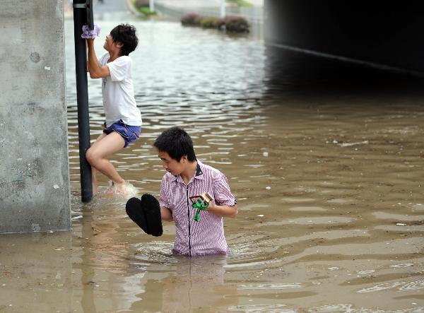 People wade through the waterlogged Jiangnan Street in Hangzhou, capital of east China's Zhejiang Province, Sept. 11, 2010. 