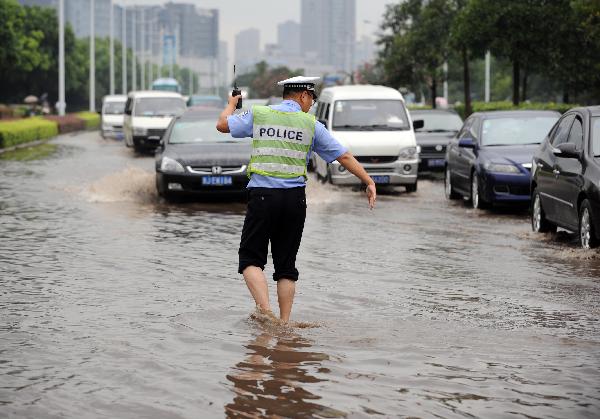 A policeman guides traffic on the waterlogged Jiangnan Street in Hangzhou, capital of east China's Zhejiang Province, Sept. 11, 2010.