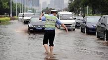 A policeman guides traffic on the waterlogged Jiangnan Street in Hangzhou, capital of east China's Zhejiang Province, Sept. 11, 2010.