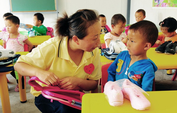 A teacher talks to a kid at a newly-built kindergarten for victims of mudslide-hit Zhouqu in Gansu Province on September 14, 2010. 