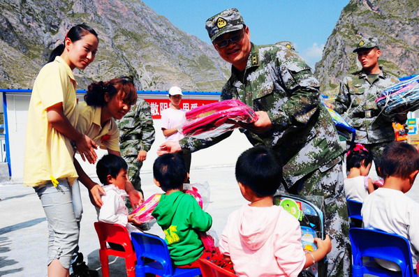 Soldiers from Lanzhou military command who assisted in the construction of the makeshift kindergarten bring school supplies to kids in Zhouqu, Gansu Province on September 14, 2010.