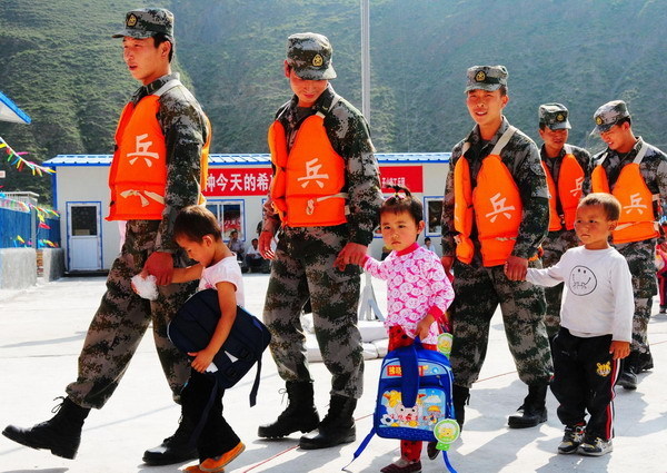 Soldiers and kids walk hand in hand to the makeshift classrooms of a newly-built kindergarten for victims of mudslide-hit Zhouqu in Gansu Province on September 14, 2010. 