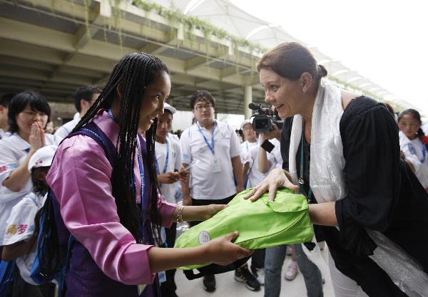 Doje Zhoima (L) from quake-hit Yushu County of northwest China's Qinghai Province receives a gift presented by an official of the Finland Pavilion at the World Expo Park in Shanghai, east China, Sept. 15, 2010. 