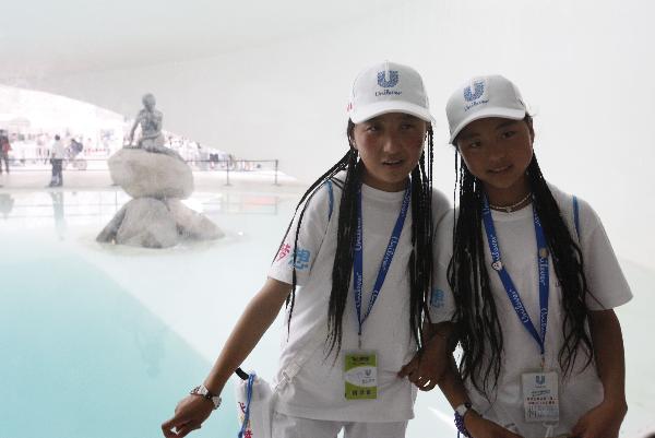 Two girls from quake-hit Yushu County of northwest China's Qinghai Province pose for a photo with the statue of Little Mermaid at the Denmark Pavilion in the World Expo Park in Shanghai, east China, Sept. 15, 2010.