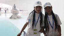 Two girls from quake-hit Yushu County of northwest China's Qinghai Province pose for a photo with the statue of Little Mermaid at the Denmark Pavilion in the World Expo Park in Shanghai, east China, Sept. 15, 2010.