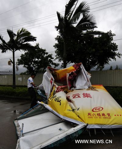A man tries to remove a damaged billboard in Zhangpu County of southeast China's Fujian Province, Sept. 20, 2010.