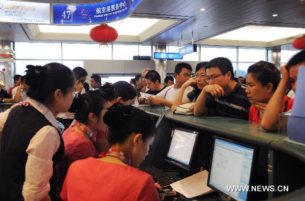 Passengers check flight information at Xiamen Airport in Xiamen, southeast China's Fujian Province, Sept. 20, 2010. 