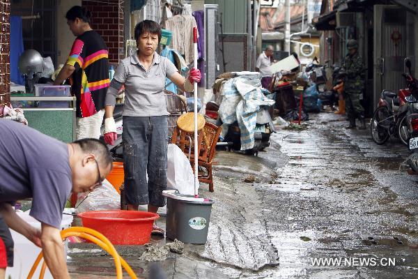 Local residents clean furnitures and articles marinated in floods in Kaohsiung County, southeast China's Taiwan, Sept. 20, 2010.