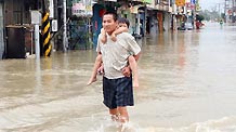 A man carrying a child on his back walks in floods in Tainan County, southeast China's Taiwan, Sept. 20, 2010.