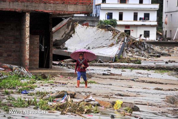 An elderly carrying a baby on the back walks in Qianpai Town in Xinyi, south China&apos;s Guangdong Province, Sept. 22, 2010. Flooding and landslides caused by Typhoon Fanabi have left 18 people dead and at least 44 still missing, according to the Ministry of Civil Affairs on Wednesday.