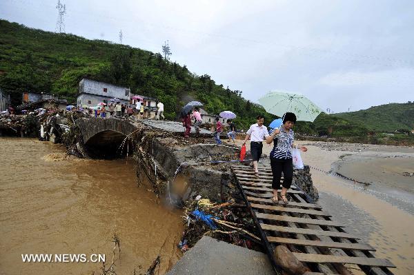 People walk across a flood-damaged bridge in Qianpai Town in Xinyi, south China&apos;s Guangdong Province, Sept. 22, 2010. Flooding and landslides caused by Typhoon Fanabi have left 18 people dead and at least 44 still missing, according to the Ministry of Civil Affairs on Wednesday.