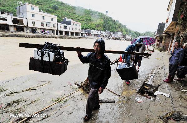 A man carrying his computer walks back home in Qianpai Town in Xinyi, south China&apos;s Guangdong Province, Sept. 22, 2010. Flooding and landslides caused by Typhoon Fanabi have left 18 people dead and at least 44 still missing, according to the Ministry of Civil Affairs on Wednesday. 