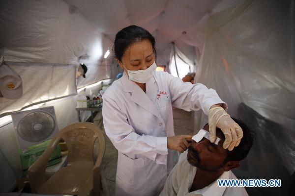 A doctor of China International Search and Rescue Team treats a patient at a tent hospital in Makly town of flood-hit Thatta in southern Pakistan, Sept. 20, 2010. 