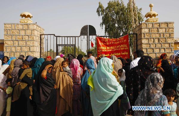 Local residents wait outside a tent hospital set by China International Search and Rescue Team in Makly town of flood-hit Thatta in southern Pakistan, Sept. 18, 2010. 