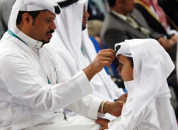 A man adjusts a turban for a boy at a ceremony marking the National Pavilion Day for Saudi Arabia at the 2010 World Expo in Shanghai, east China, Sept. 23, 2010.