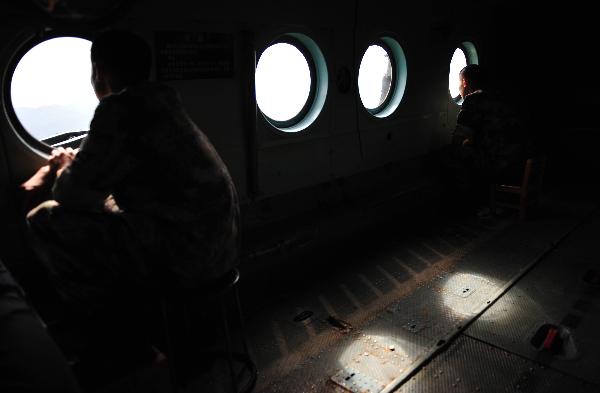 Soldiers look out of portholes on a military helicopter on their way back from conducting an air-drop duty in Xinyi, south China&apos;s Guangdong Province, Sept. 25, 2010. Since torrential rainstorm brought by Typhoon Fanabi hit Guangdong this week and caused serious waterlog, China&apos;s army aviation regiment has bridged an air lifeline by airdropping daily necessities to disaster-stricken people.